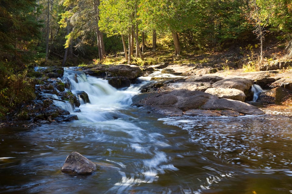 Un río sinuoso con rocas y árboles en una zona boscosa.