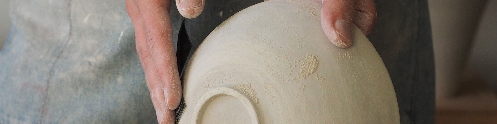 Unrecognizable woman ceramist peeling a clay plate holding sponge. The process of irregularities and grinding of the finished product. Small business, hobby, ceramic concept.