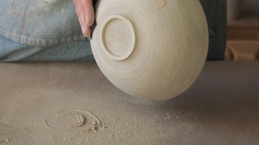 Unrecognizable woman ceramist peeling a clay plate holding sponge. The process of irregularities and grinding of the finished product. Small business, hobby, ceramic concept.