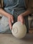 Unrecognizable woman ceramist peeling a clay plate holding sponge. The process of irregularities and grinding of the finished product. Small business, hobby, ceramic concept.