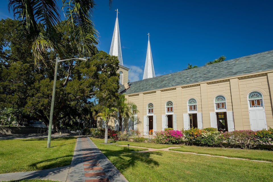 Een kerk met een hoge spits en een verzorgd gazon ervoor.