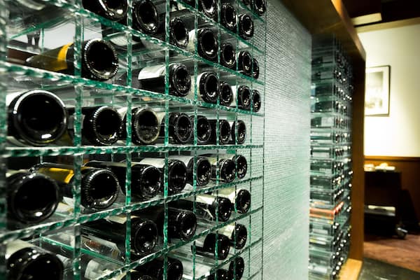 Modern Wine Cellar rack with many tens bottles brand on shelf and put on temper thick glass shelf, in temperature control room to keep winecellar fresh long time