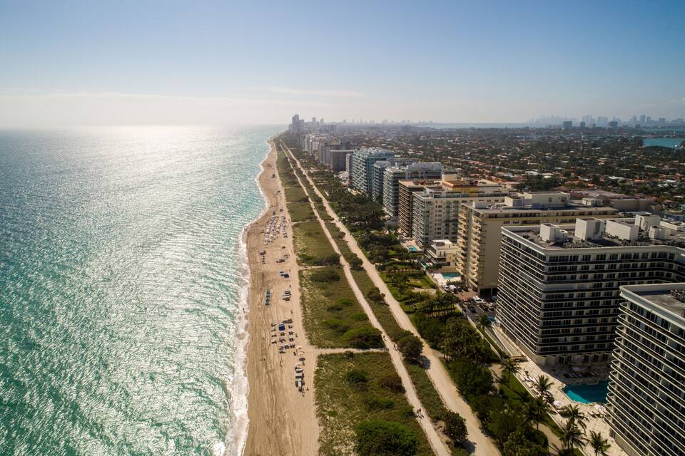 Un paisaje urbano costero con playa, edificios altos y una vista despejada del océano.