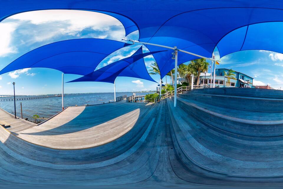 A skate park with blue canopies and a view of the ocean.