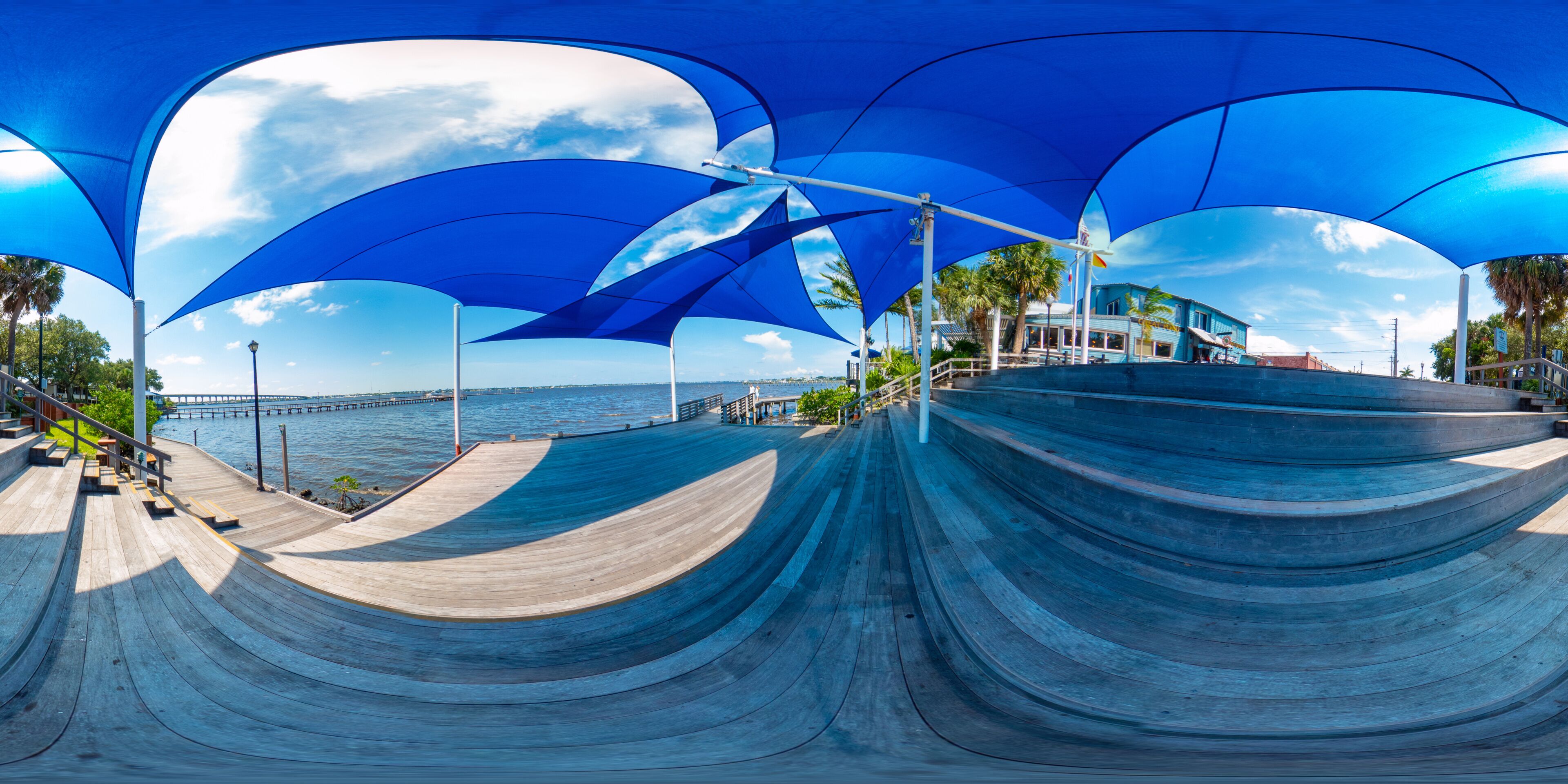 A skate park with blue canopies and a view of the ocean.