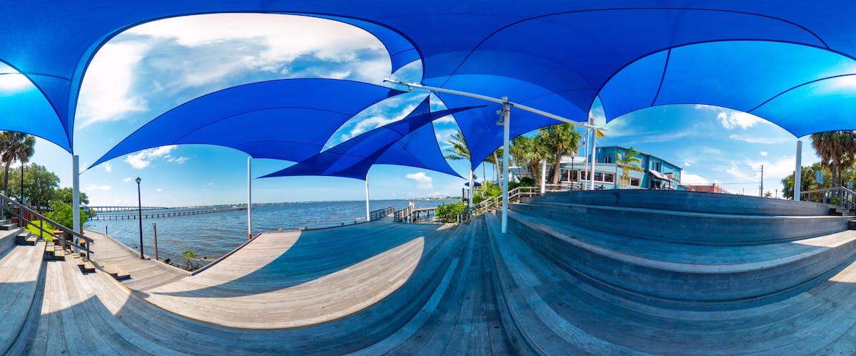 A skate park with blue canopies and a view of the ocean.