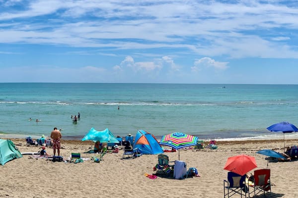Une plage où l’on peut voir des gens se prélasser au soleil, des parasols et des tentes.