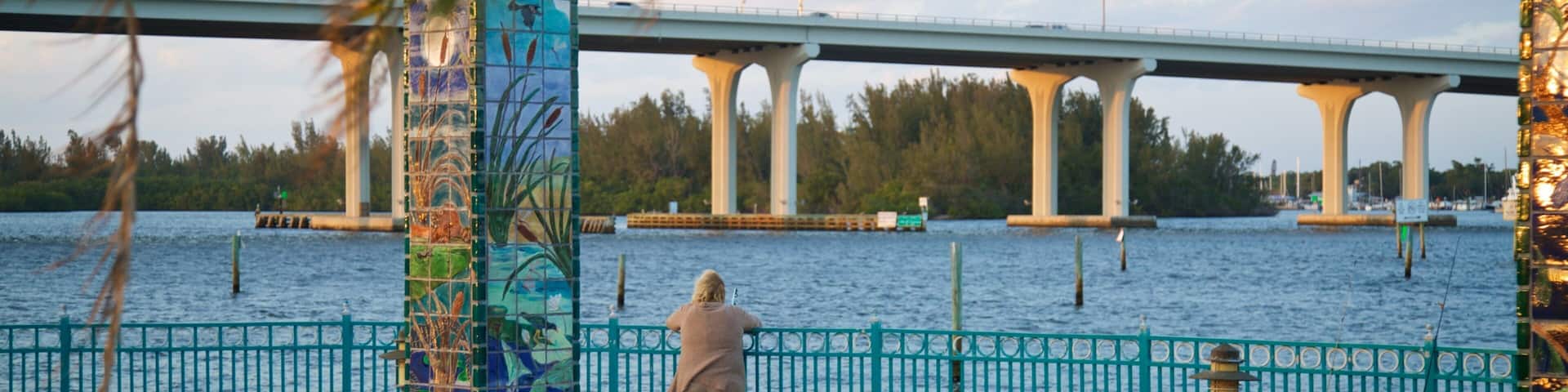 A bridge over water, a tiled fence, and a person fishing.