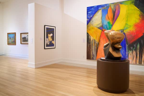 Eine Kunstgalerie mit Holzböden und verschiedenen Gemälden und Skulpturen.