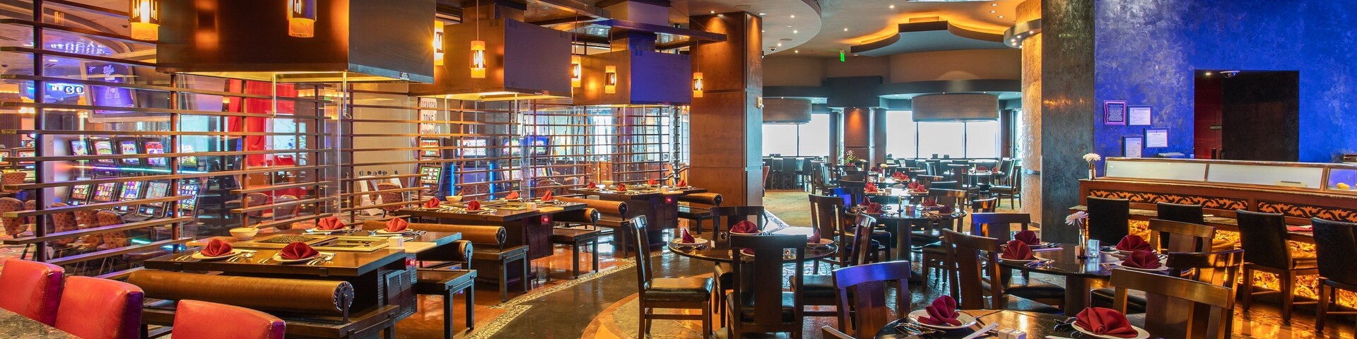 Um restaurante espaçoso com várias áreas de refeições, um bar e uma sala de jogos com máquinas de slot.