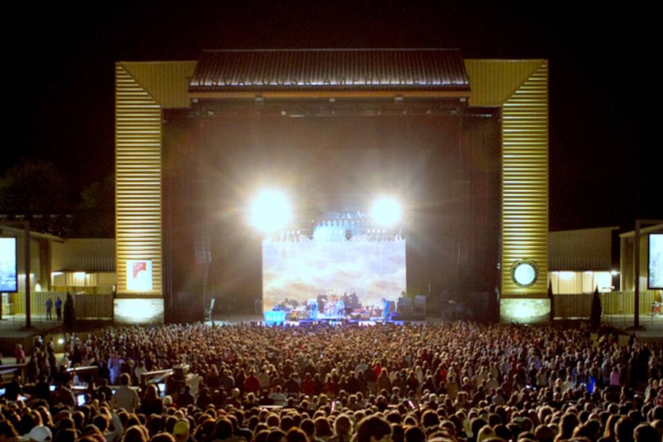 A large outdoor concert with a stage and a crowd.