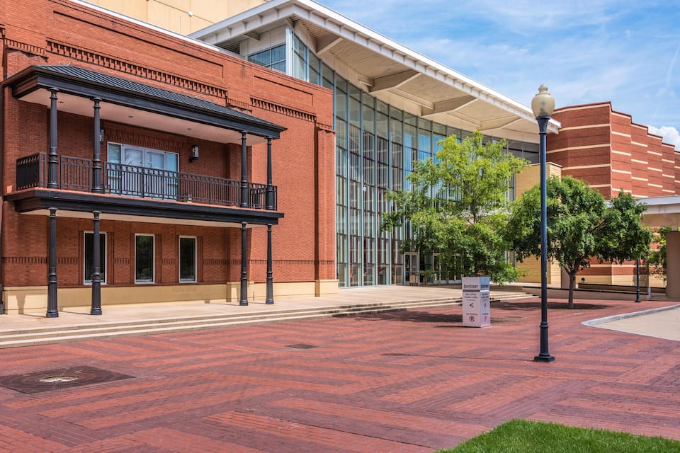 A red brick building with a balcony, large windows, and a modern glass extension.