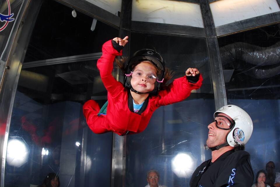 A person in a red jumpsuit and helmet, suspended in mid-air, likely in a bungee jumping activity.