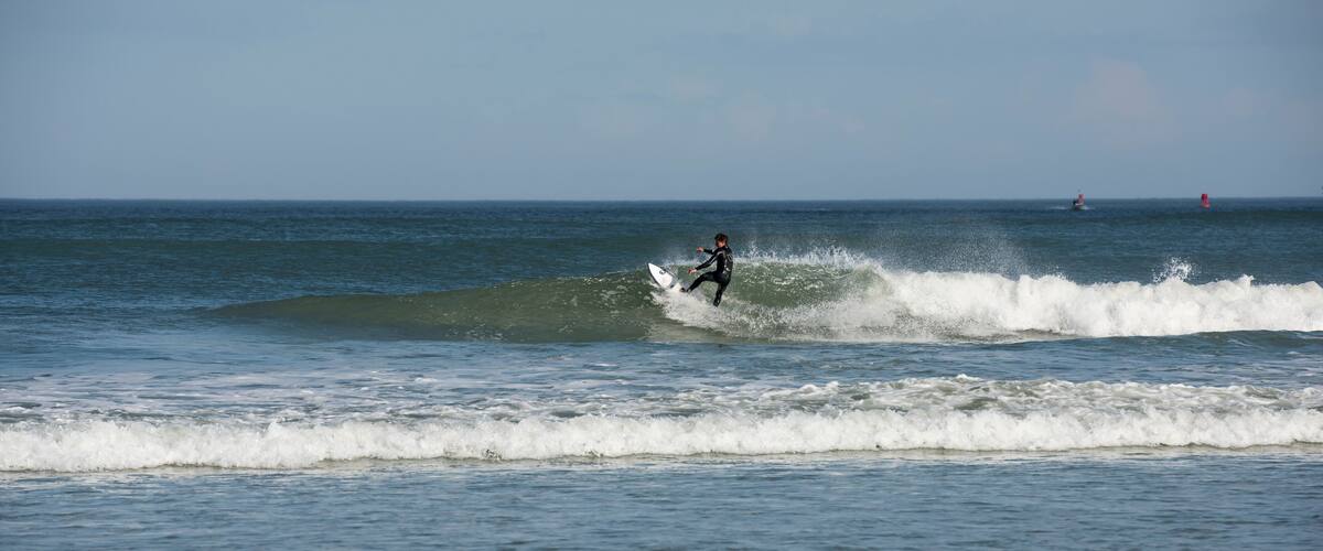 A lone male surfer wearing a black wet suit cutting back on wave as he surfs Florida's east coast near Daytona Beach, USA.