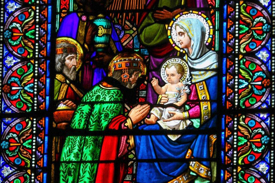 A stained glass window with religious figures and floral patterns.