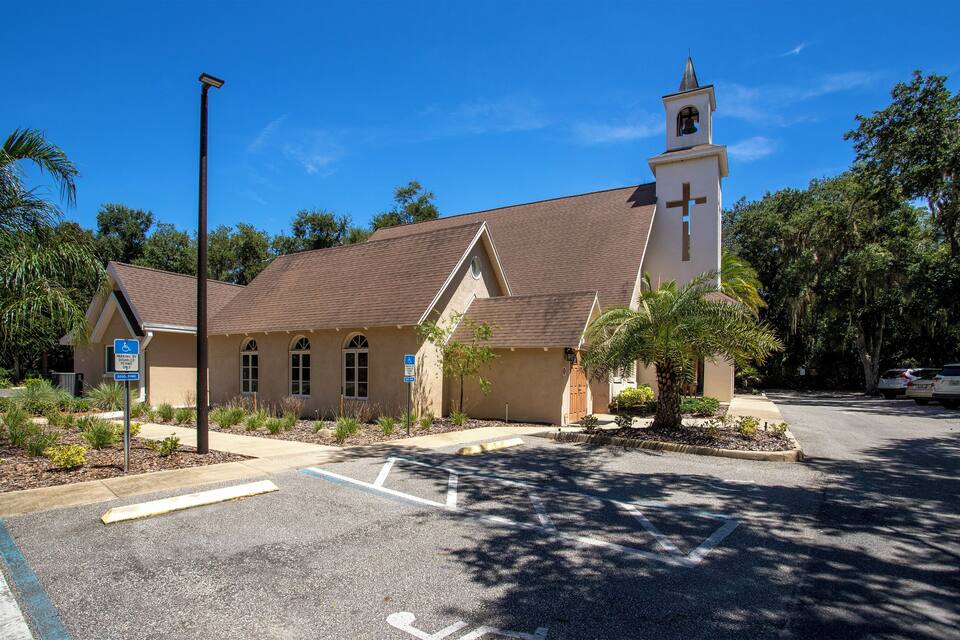 A church with a bell tower and a parking lot.