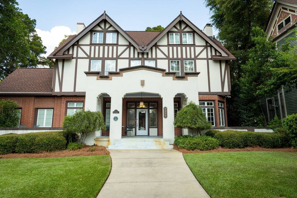 A Tudor-style house with a brick facade, white trim, and a symmetrical design.