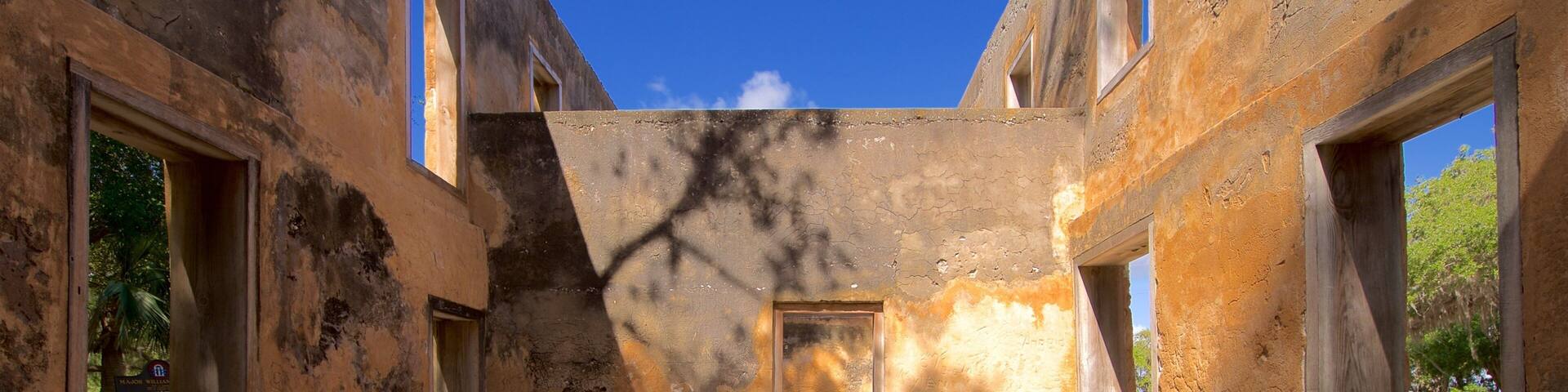 An abandoned building with peeling walls, gravel floor, and multiple windows.