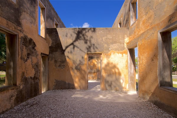 An abandoned building with peeling walls, gravel floor, and multiple windows.
