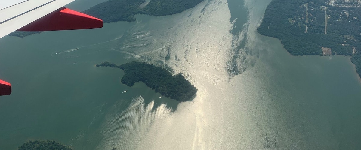 An airplane wing with the logo 'Southwest.com' flying over a coastal area with numerous islands and water bodies.