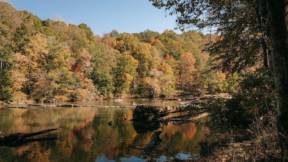 A calm river surrounded by autumn-colored trees.