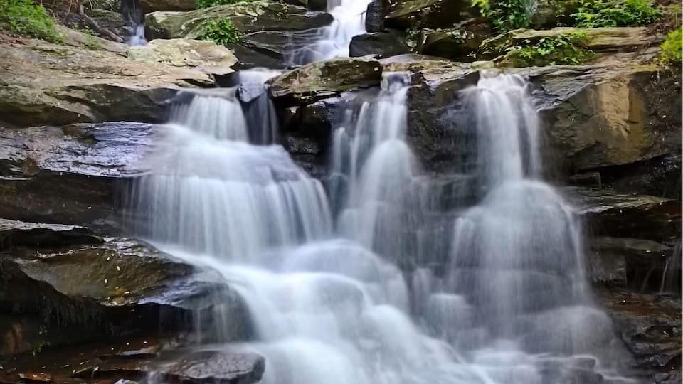 A waterfall cascading over rocks in a forested area.