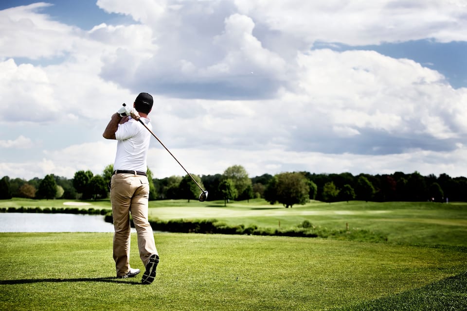 A golfer on a golf course with a lake in the background.