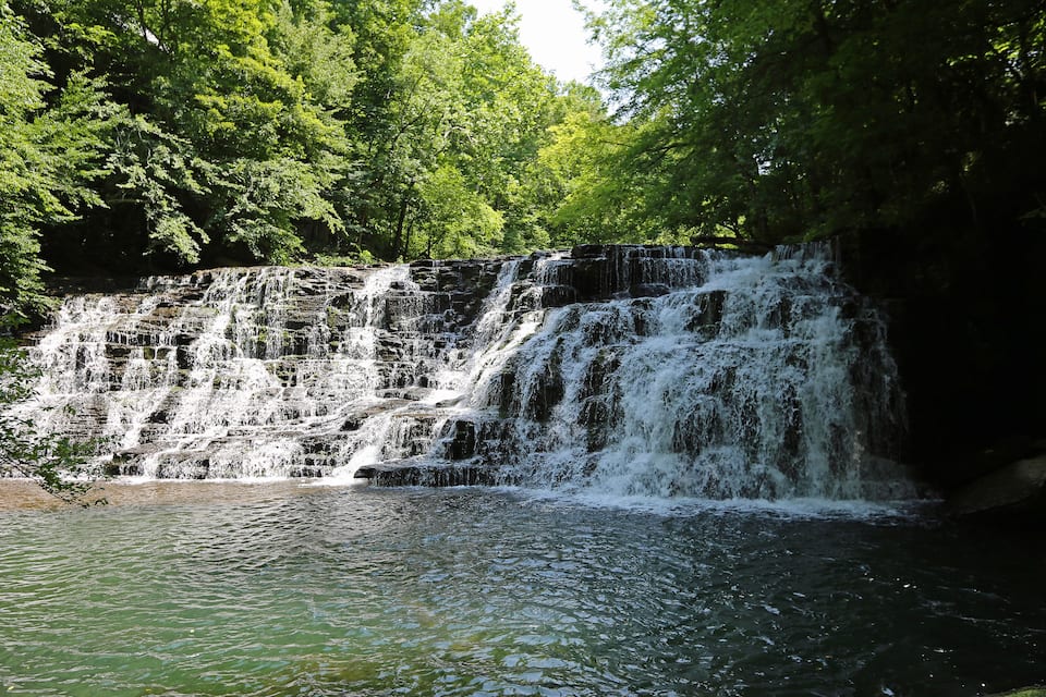 Una cascada de diversos nivells envoltada de vegetació verda i abundant.