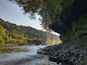 Un río serpenteando por un valle boscoso con un acantilado rocoso a un lado.