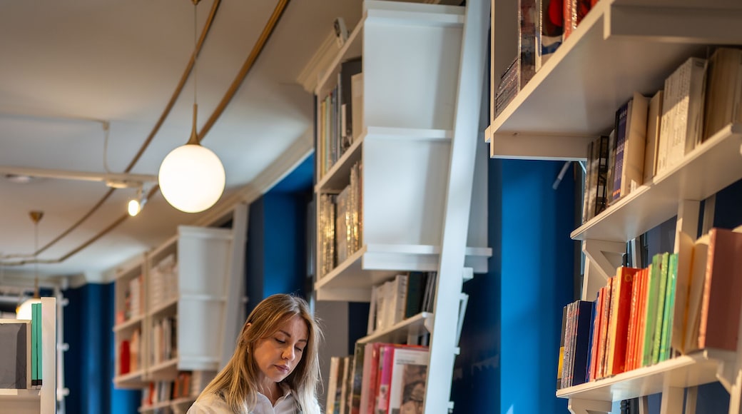Enthusiastic woman selects books in bookstore alone. Female book lover browsing, searching textbooks, handbooks, library visit, book fair, book crossing, literature passion, bibliophile in store