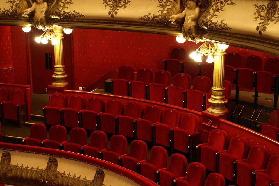 A theater with red velvet seats and ornate gold detailing.