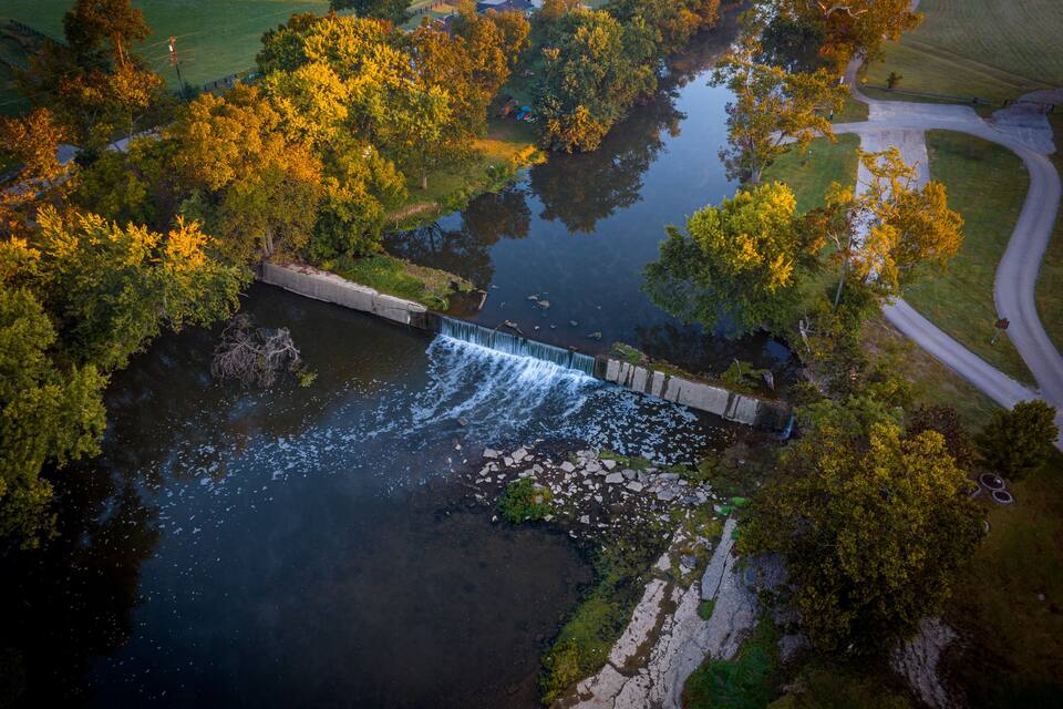 A river flowing through a park with trees and a bridge.