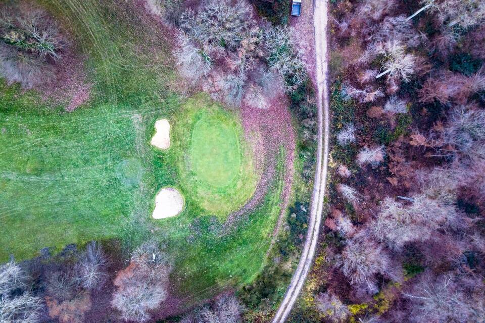 Vista aèria d'un camp de golf amb búnquers de sorra i una carretera al costat.
