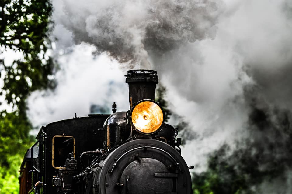 A steam locomotive with a glowing headlight, emitting steam.