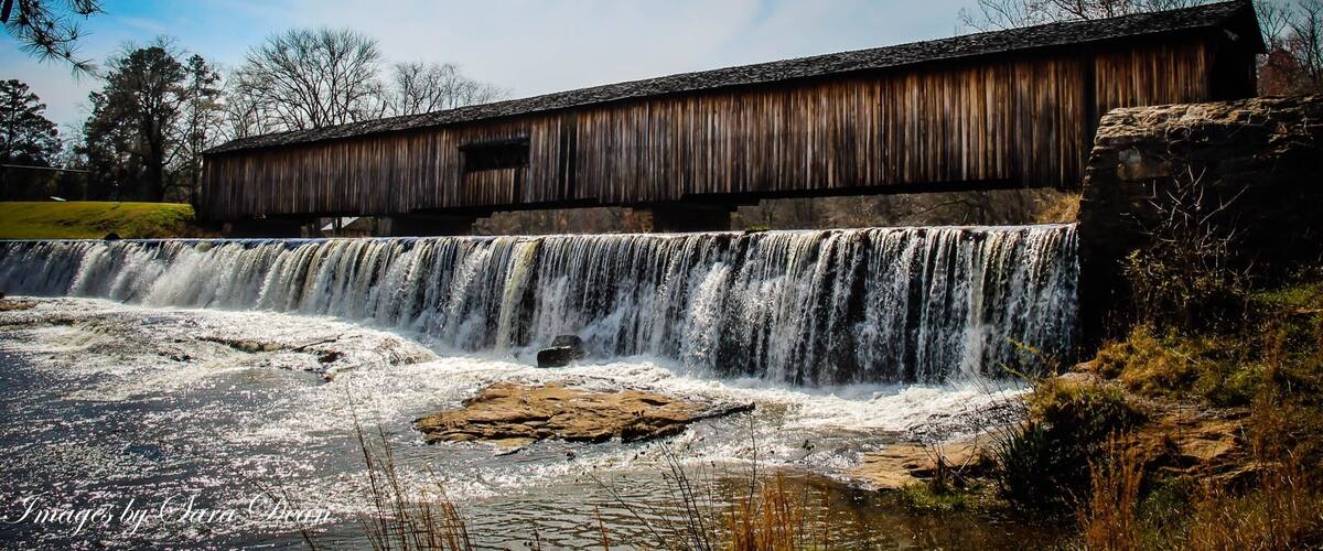 A wooden covered bridge over a waterfall.