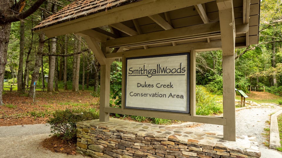 A wooden signboard with the text "Smithgall Woods, Dukes Creek Conservation Area" in a forested setting.