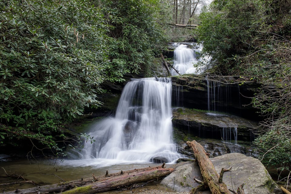 A waterfall cascading over rocks in a forested area.