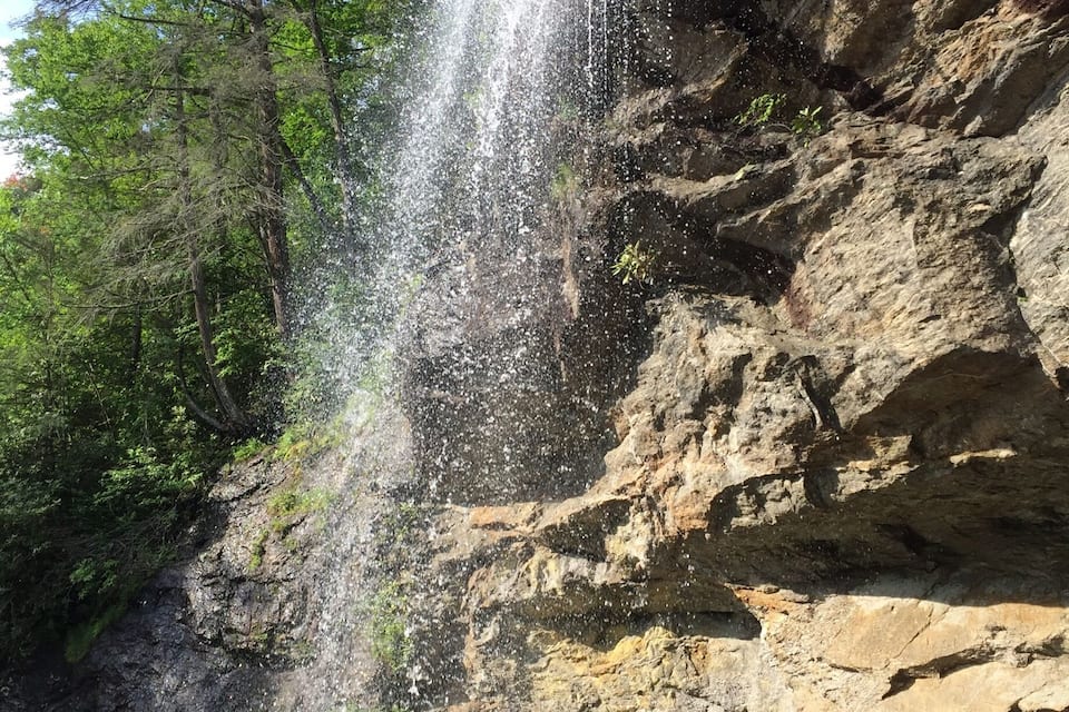 Une cascade se déversant le long d’une falaise rocheuse, entourée d’une végétation luxuriante.