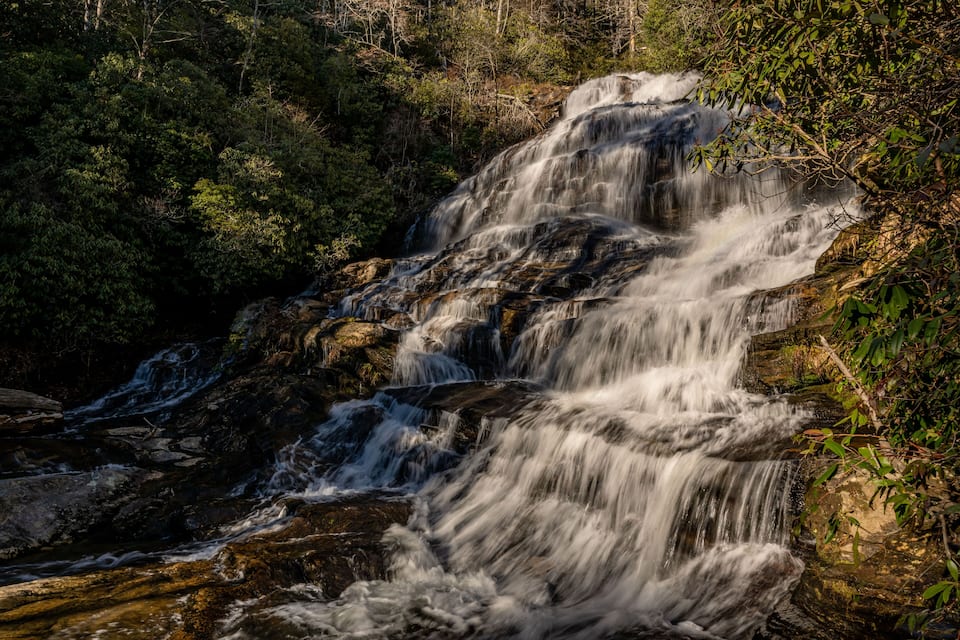 A waterfall cascading over rocks in a forested area.