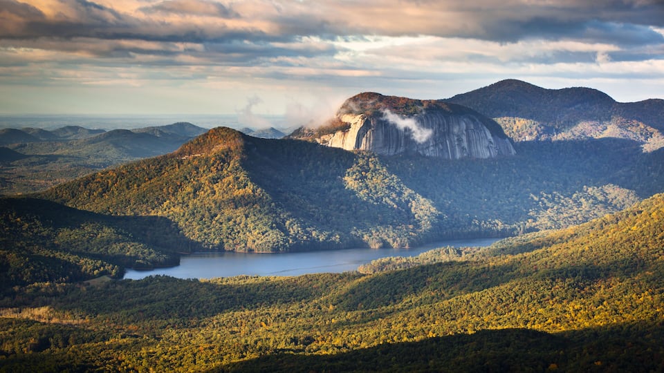A mountainous landscape with a lake and a prominent cliff.