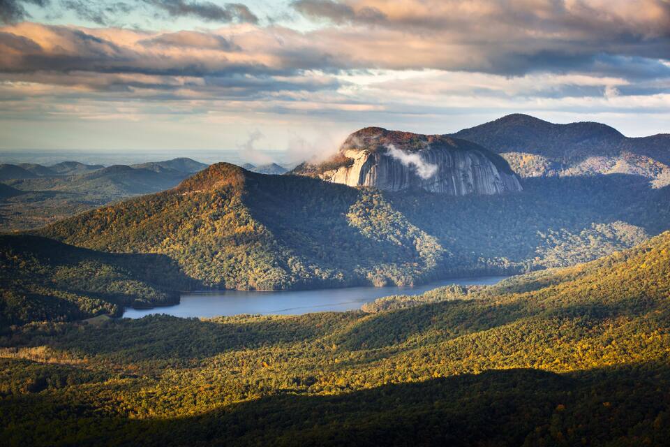 A mountainous landscape with a lake and a prominent cliff.