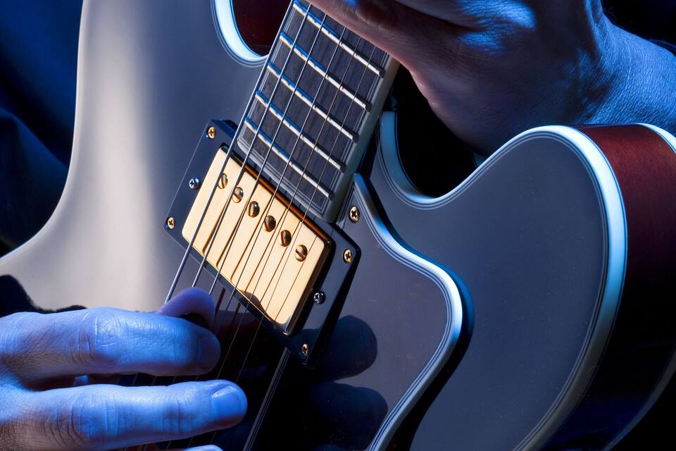 Een persoon speelt een elektrische gitaar.