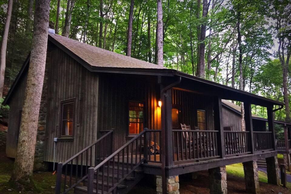 A rustic cabin with a wooden exterior, a porch, and a staircase leading to the entrance.