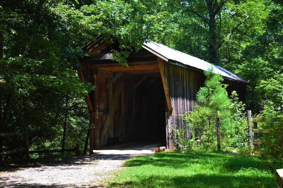 A covered bridge surrounded by lush greenery.