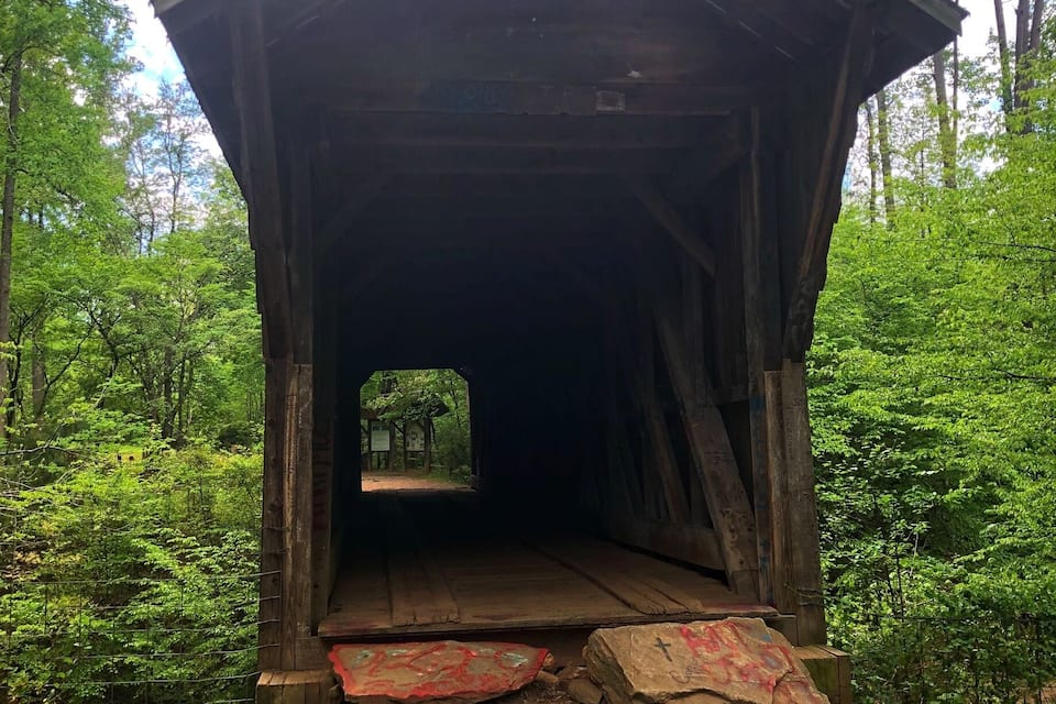 A wooden covered bridge in a forest.