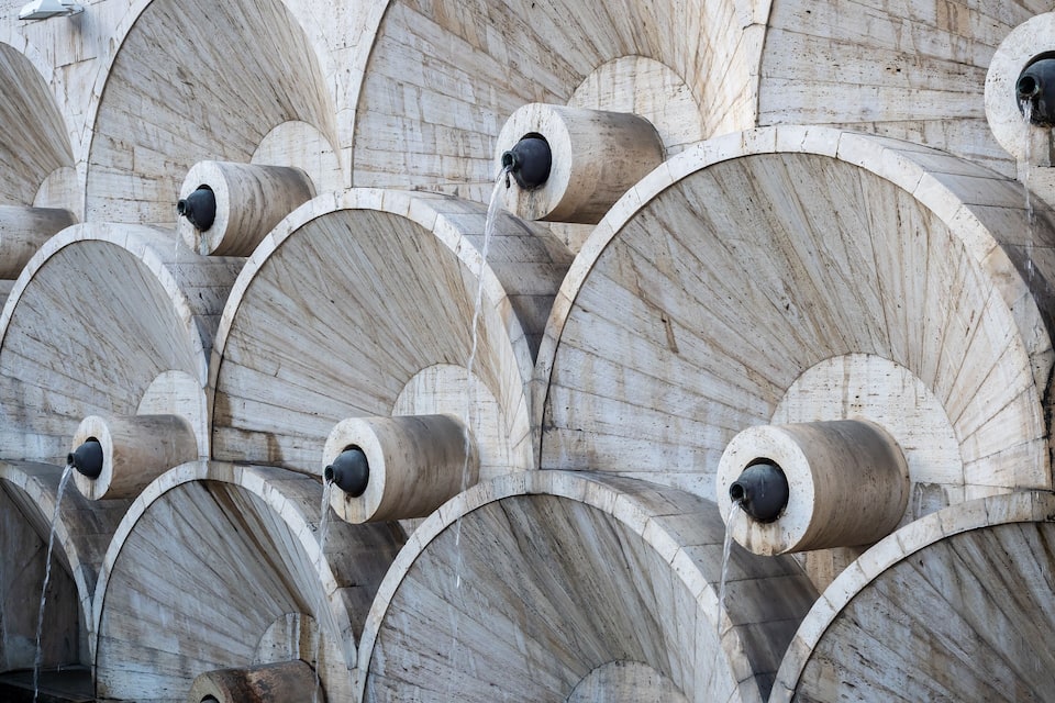 A series of large, arched stone structures with water flowing from multiple spouts.