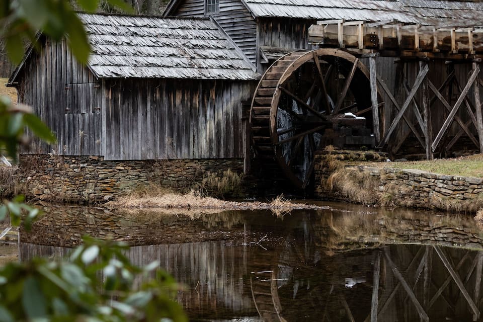 A wooden water wheel and mill structure by a calm river.