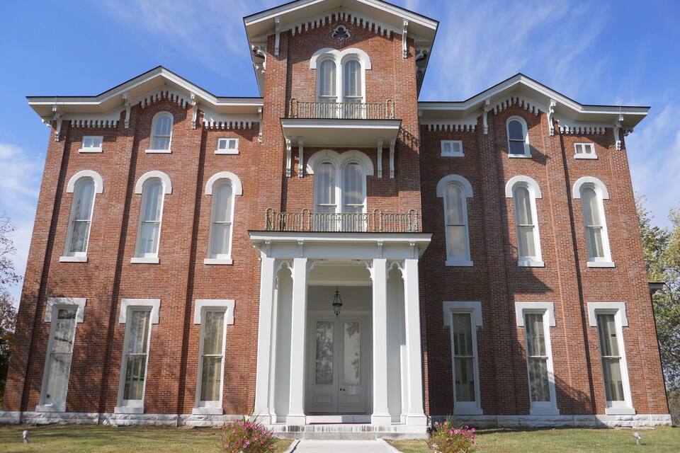 A large, red brick building with white trim and a central entrance flanked by columns.
