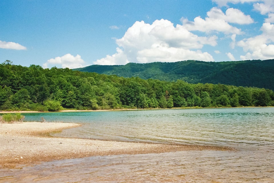 A lake surrounded by dense green forest and hills.