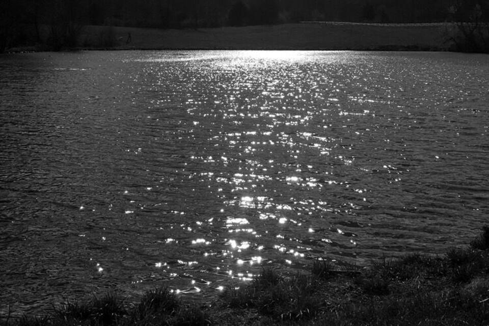 A body of water reflecting sunlight with clouds in the sky.